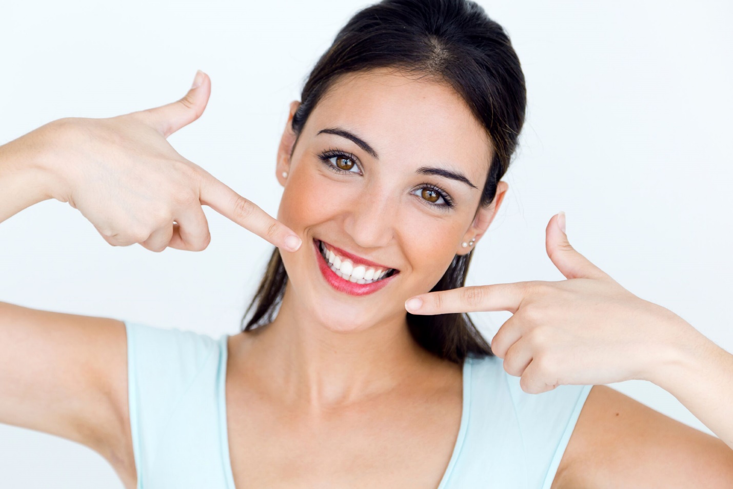 young woman with veneers in Corte Madera pointing to her smile