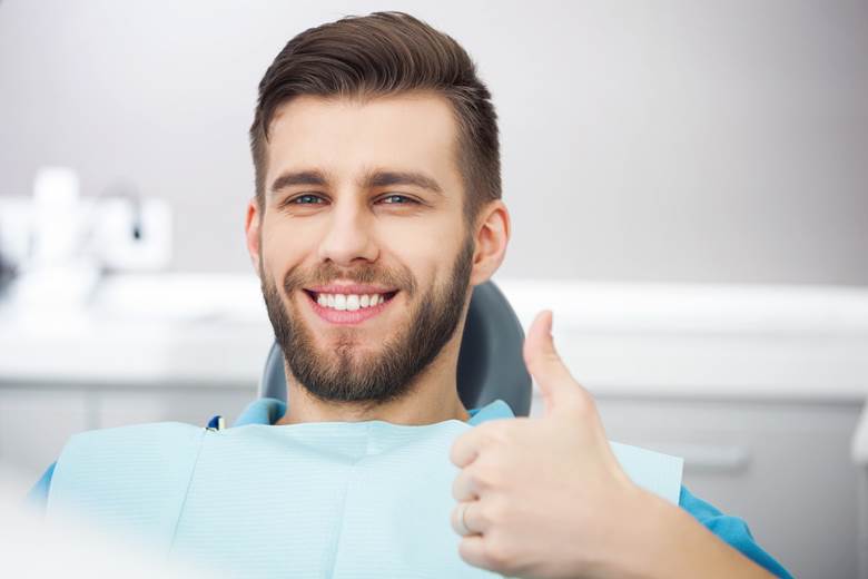 Man giving thumbs up in dentist’s chair