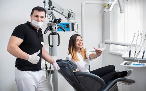 Woman and dentist giving thumbs up