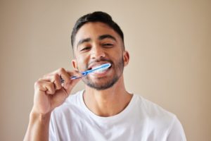 young adult brushing their teeth