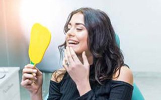 dental patient admiring her smile in a mirror