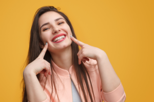 Happy young woman pointing to her teeth