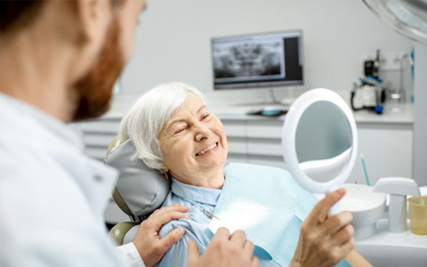 Older woman looking at her smile at the dentist’s office   