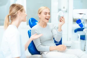Woman with blonde hair sitting in dental chair smiling and her resutls