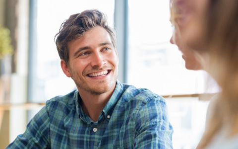 man smiling while talking to friend  