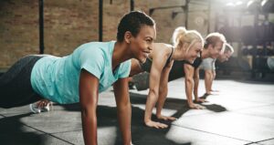 Four people in a row doing planks at the gym